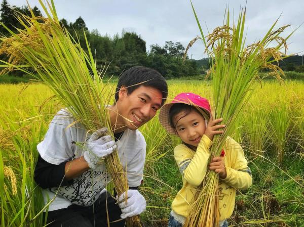 田んぼでほほ笑む大滝義隆さんと子ども